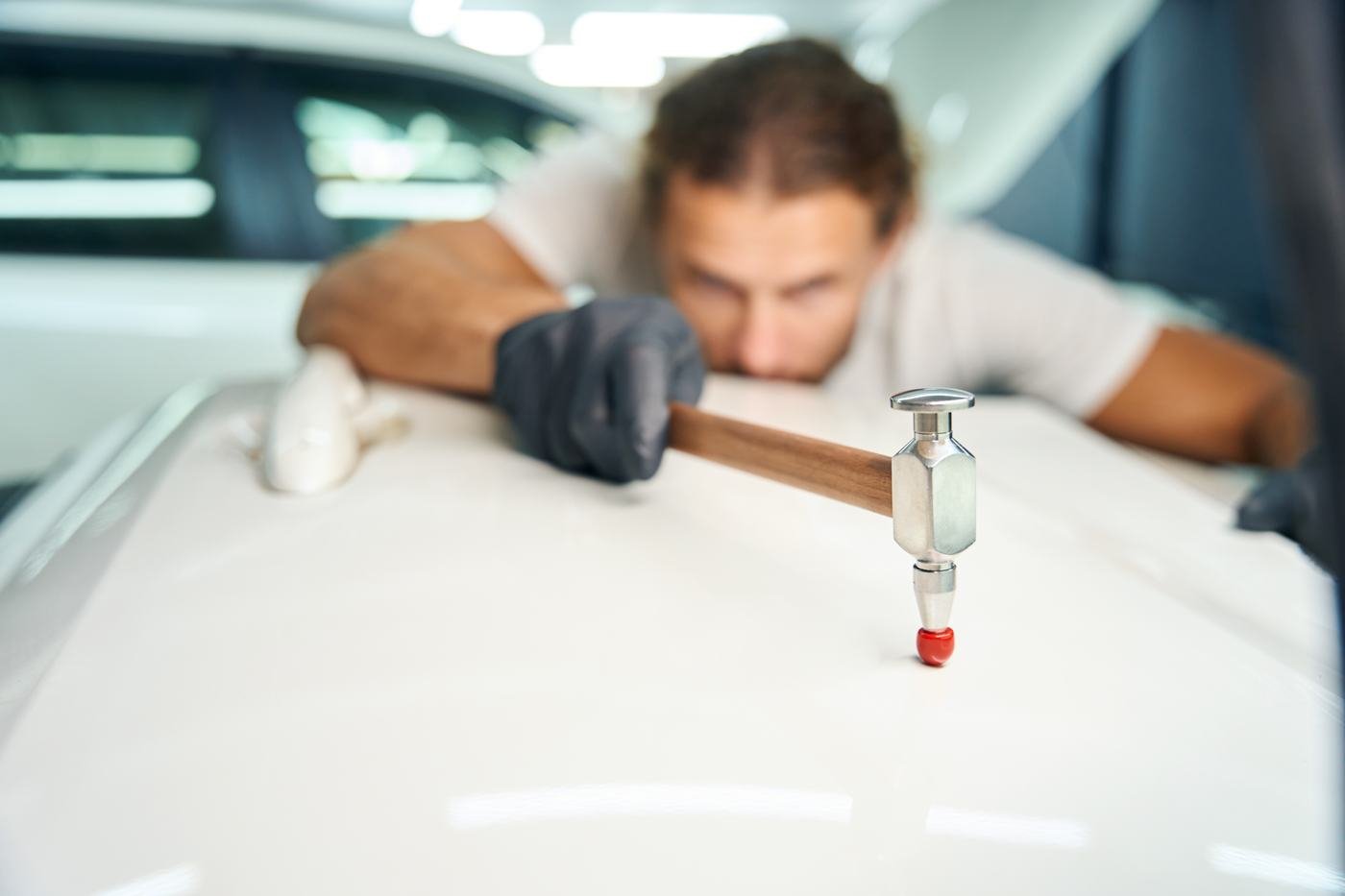 Profissional reparando a lataria de um carro com ferramenta específica